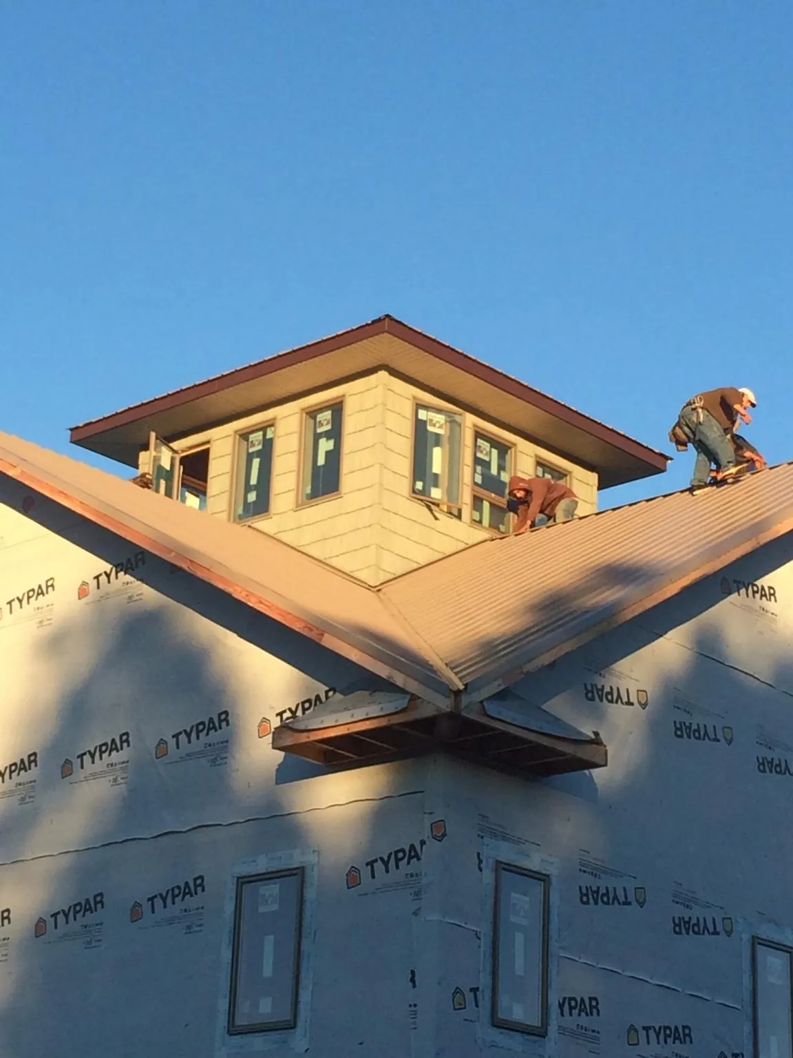 Roofers working around a rooftop cupola on a new metal roof at sunset — Roof Waterproofing in Cheltenham by Roofing Brothers